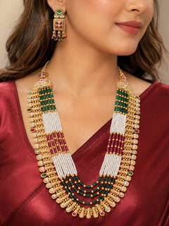Close-up of a women wearing an ornate traditional (Gold Polish) Pink & Green Long jewellery set and earrings with Pearls, Green & Pink Crystal Beads and Meenakari. Festive Diwali outfit paired with a colorful Meenakari necklace. Wedding function styling with a premium Meenakari imitation necklace.