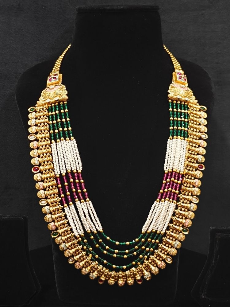 Close-up of an ornate traditional (Gold Polish) Pink & Green Long jewellery set and earrings with Pearls, Green & Pink Crystal Beads and Meenakari. Festive Diwali outfit paired with a colorful Meenakari necklace. Wedding function styling with a premium Meenakari imitation necklace.
