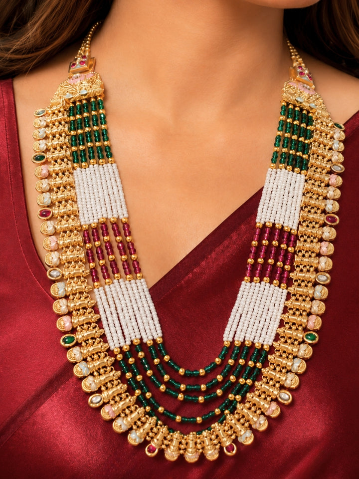 Close-up of a women wearing an ornate traditional (Gold Polish) Pink & Green Long jewellery set and earrings with Pearls, Green & Pink Crystal Beads and Meenakari. Festive Diwali outfit paired with a colorful Meenakari necklace. Wedding function styling with a premium Meenakari imitation necklace.