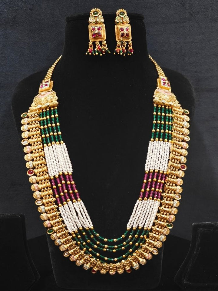 Close-up of an ornate traditional (Gold Polish) Pink & Green Long jewellery set and earrings with Pearls, Green & Pink Crystal Beads and Meenakari. Festive Diwali outfit paired with a colorful Meenakari necklace. Wedding function styling with a premium Meenakari imitation necklace.