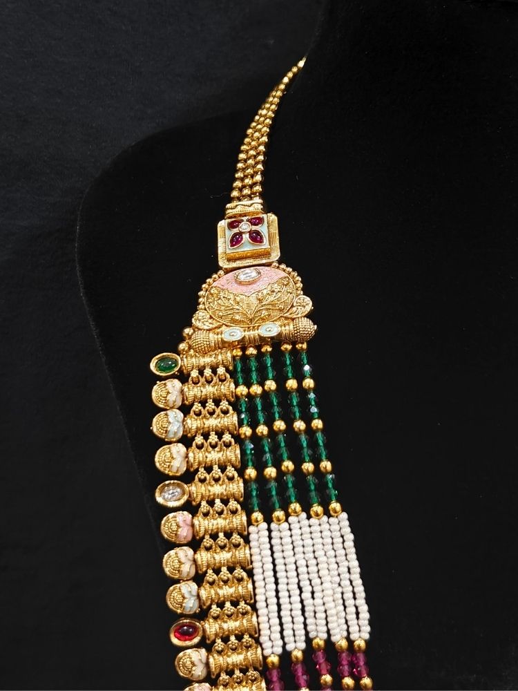 Close-up of an ornate traditional (Gold Polish) Pink & Green Long jewellery set and earrings with Pearls, Green & Pink Crystal Beads and Meenakari. Festive Diwali outfit paired with a colorful Meenakari necklace. Wedding function styling with a premium Meenakari imitation necklace.