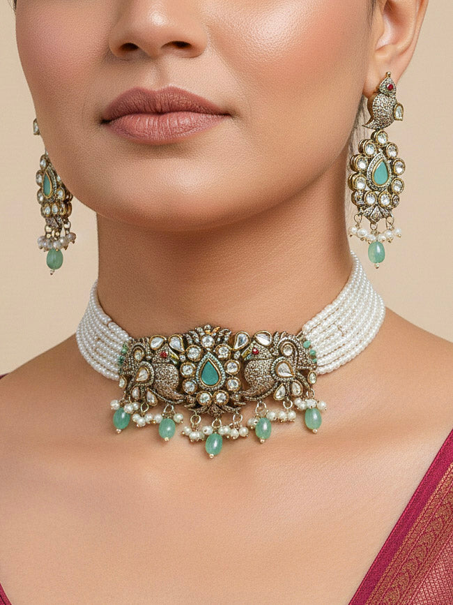 Close-up of a woman wearing an ornate traditional Mint Green (Mehendi Polish)  Choker Diamond jewellery set and earrings with Pearls, Tumble Beads, American Diamond, Kundan and Mint Green Colored Stones. Festive Diwali outfit styled with an American diamond artificial necklace. Close-up of high-quality  artificial American Diamond necklace craftsmanship.