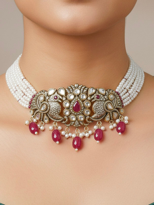 Close-up of a woman wearing an ornate traditional Ruby Red (Mehendi Polish)  Choker Diamond jewellery set and earrings with Pearls, Tumble Beads, American Diamond, Kundan and Ruby Red Colored Stones. Festive Diwali outfit styled with an American diamond artificial necklace. Close-up of high-quality  artificial American Diamond necklace craftsmanship.