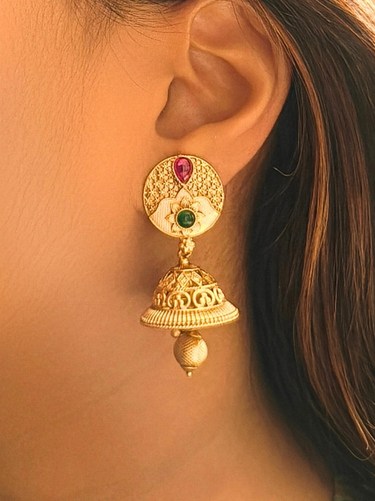 Close-up of a woman wearing an ornate traditional (Gold Polish) Earrings set with Colored Stone. Saree look completed with an elegant Colored Stone artificial jewelry piece. Woman wearing trending Colored Stone artificial jewelry for wedding season in India.