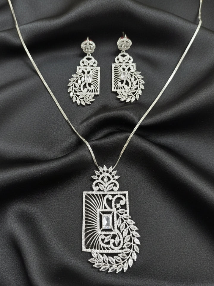 Close-up of an ornate Western (Silver Polish) Diamond Pendant set and earrings with American Diamonds. Elegant festive look with a high-quality imitation American diamond Pendant set. Close-up of a cocktail party look featuring a premium American diamond Pendant.