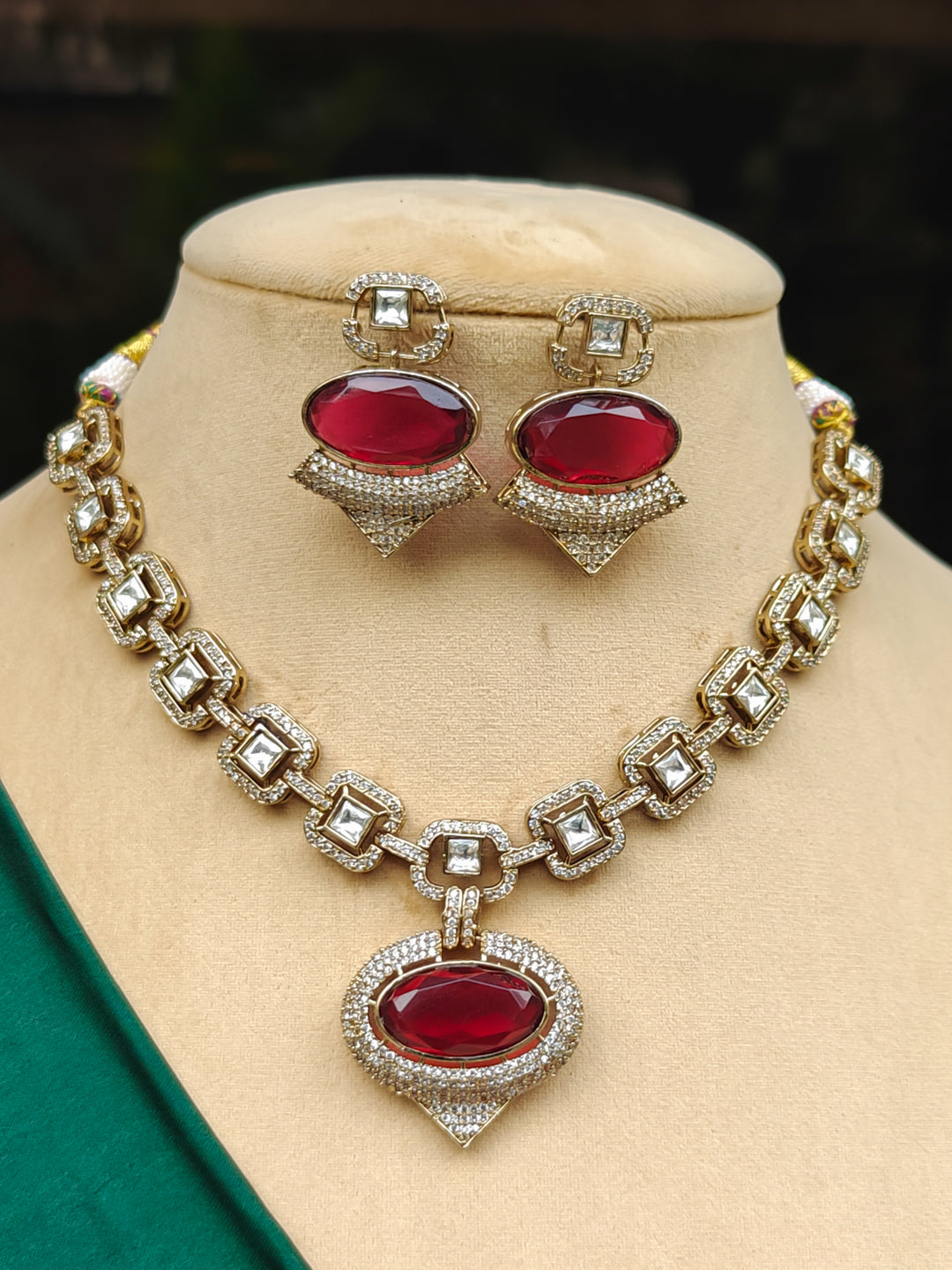 "A woman in a traditional saree, wearing a gorgeous artificial diamond and polki with red colored stone necklace paired with diamond earrings. This artificial diamond jewelry set offers a traditional yet modern touch for Indian brides, designed to add elegance and sophistication to any occasion."