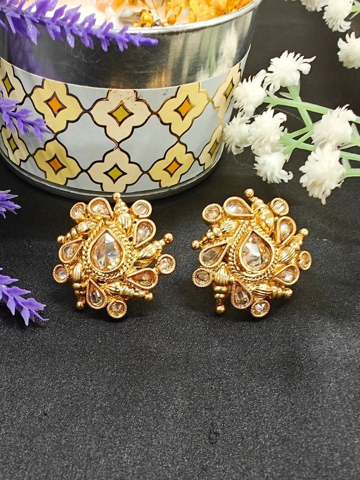 Eliza Earrings showcase intricate floral designs with reverse American diamond accents, displayed on Black Surface with White and a Purple flower in the background.