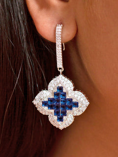 Close-up of a woman wearing an ornate  Western (Silver Polish) Blue Diamond  Earrings with American Diamond and Colored stones. Elegant party wear styled with high-quality imitation American Diamond earrings. Close-up of American diamond earrings styled for a reception party.