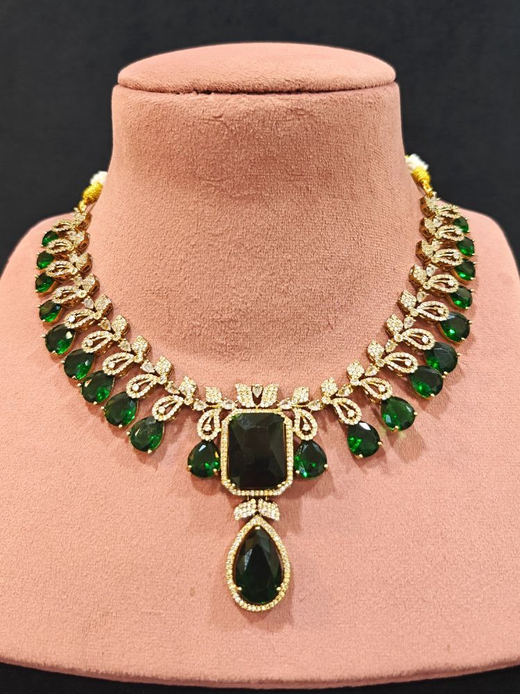 A stunning affordable artificial diamond and emerald green colored stone necklace and matching earrings set, perfect for wedding guests and formal events. This luxury artificial diamond jewelry provides the brilliance of real diamonds at a fraction of the cost. Festive Diwali outfit styled with an American diamond artificial necklace.