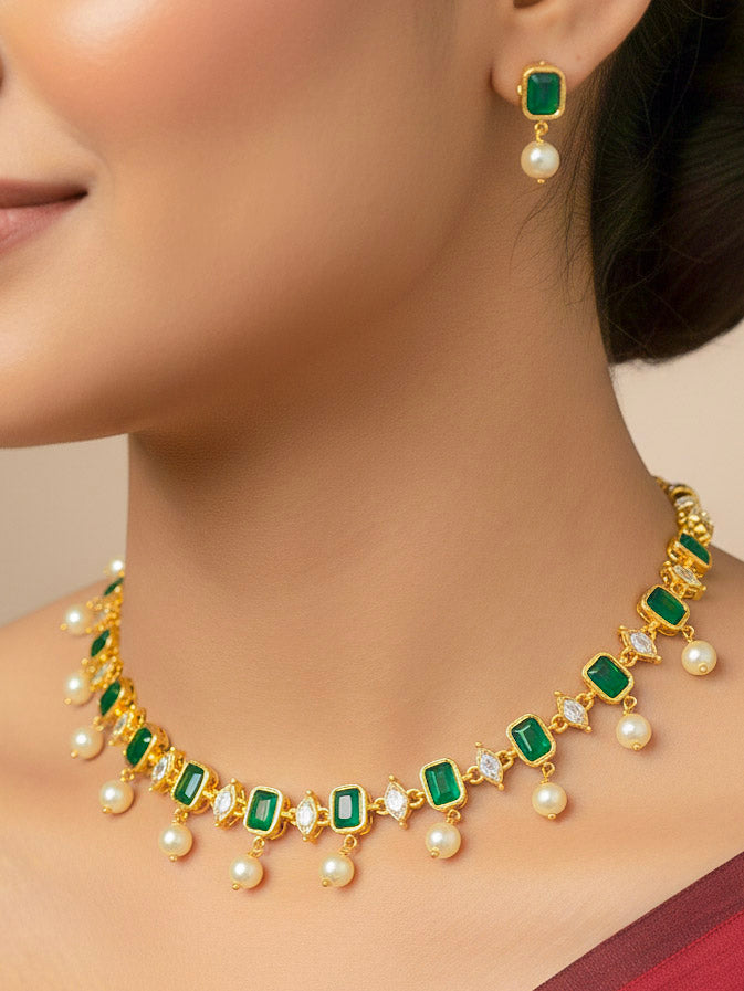 Close-up of a woman wearing an ornate traditional (Gold Polish) Emerald Green Choker jewellery set and earrings with Colored Stones, Pearl and American Diamonds. Festive Diwali outfit styled with an Colored Stones artificial necklace. Mehendi function outfit styled with a Colored Stone  necklace set.