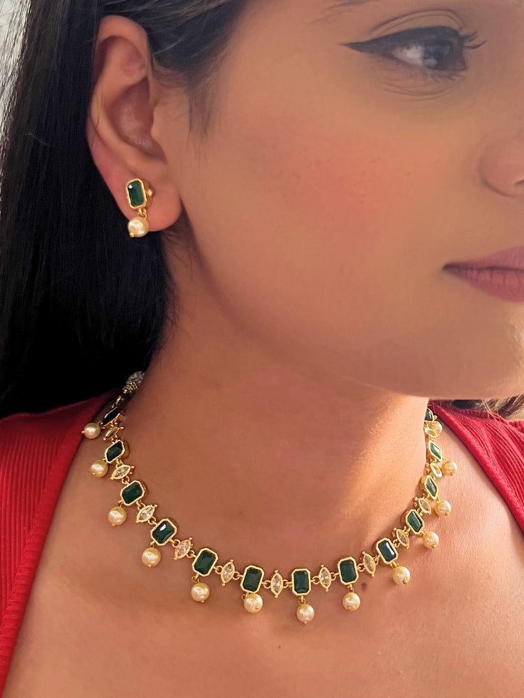 Close-up of a woman wearing the 
Emerald Green Amelia Choker Necklace adorned with colored gemstones and dangling pearls, matching earrings, and a Emerald Green top—an elegant choice for wedding ceremonies. Her lips are lightly colored, with dark hair partially visible.