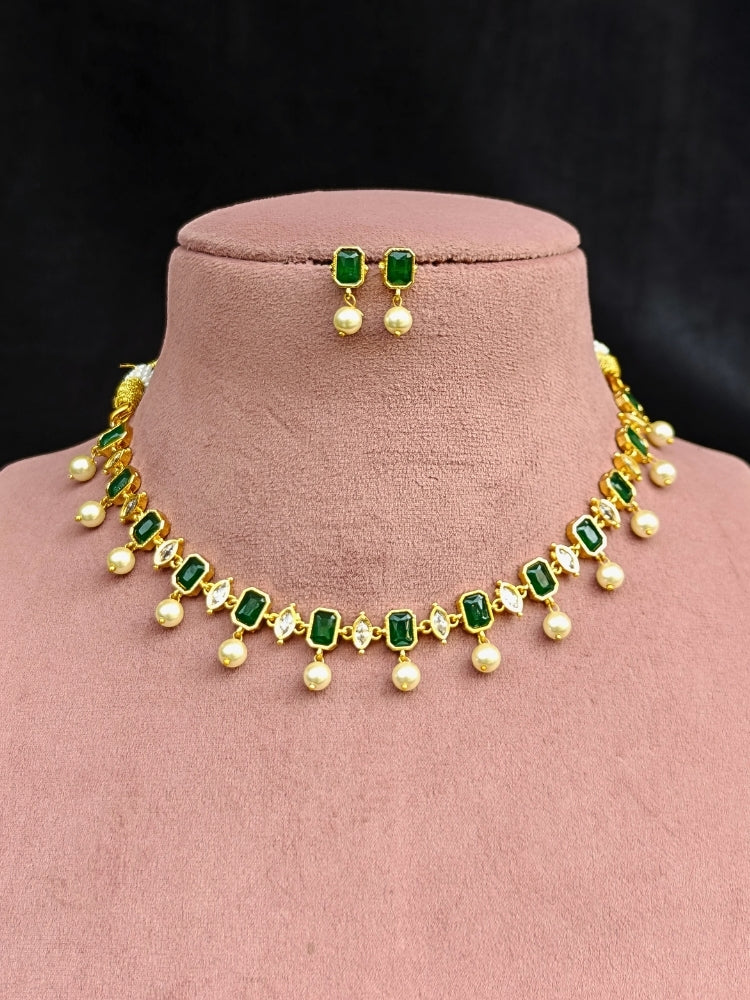 Close-up of an ornate traditional (Gold Polish) Emerald Green Choker jewellery set and earrings with Colored Stones, Pearl and American Diamonds. Festive Diwali outfit styled with an Colored Stones artificial necklace. Mehendi function outfit styled with a Colored Stone  necklace set.