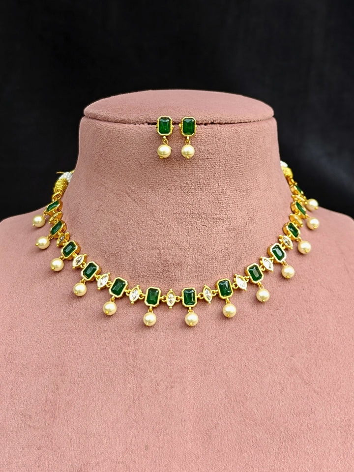 Close-up of an ornate traditional (Gold Polish) Emerald Green Choker jewellery set and earrings with Colored Stones, Pearl and American Diamonds. Festive Diwali outfit styled with an Colored Stones artificial necklace. Mehendi function outfit styled with a Colored Stone  necklace set.