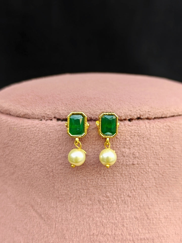 Close-up of an ornate traditional (Gold Polish) Emerald Green Choker jewellery set and earrings with Colored Stones, Pearl and American Diamonds. Festive Diwali outfit styled with an Colored Stones artificial necklace. Mehendi function outfit styled with a Colored Stone  necklace set.