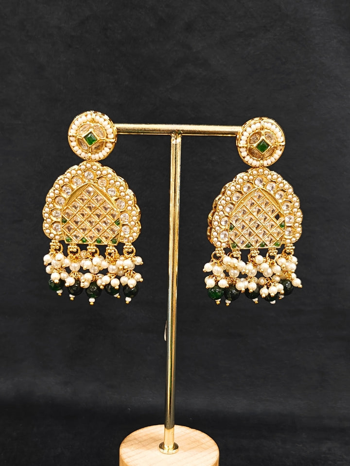 Close-up of an ornate traditional Green Rajwadi gold Long jewellery set and earrings with American Diamonds, Pearls, Crystal stones, Green colored stones. Close-up of a premium Rajwadi artificial necklace under 10000. Reception party look featuring a statement Rajwadi necklace.