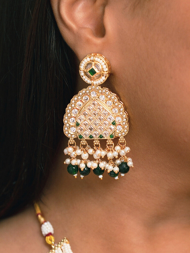 Close-up of a woman wearing an ornate traditional Green Rajwadi gold Long jewellery set and earrings with American Diamonds, Pearls, Crystal stones, Green colored stones. Woman styled in a royal Rajwadi artificial necklace set for a traditional Indian wedding. Reception party look featuring a statement Rajwadi necklace.