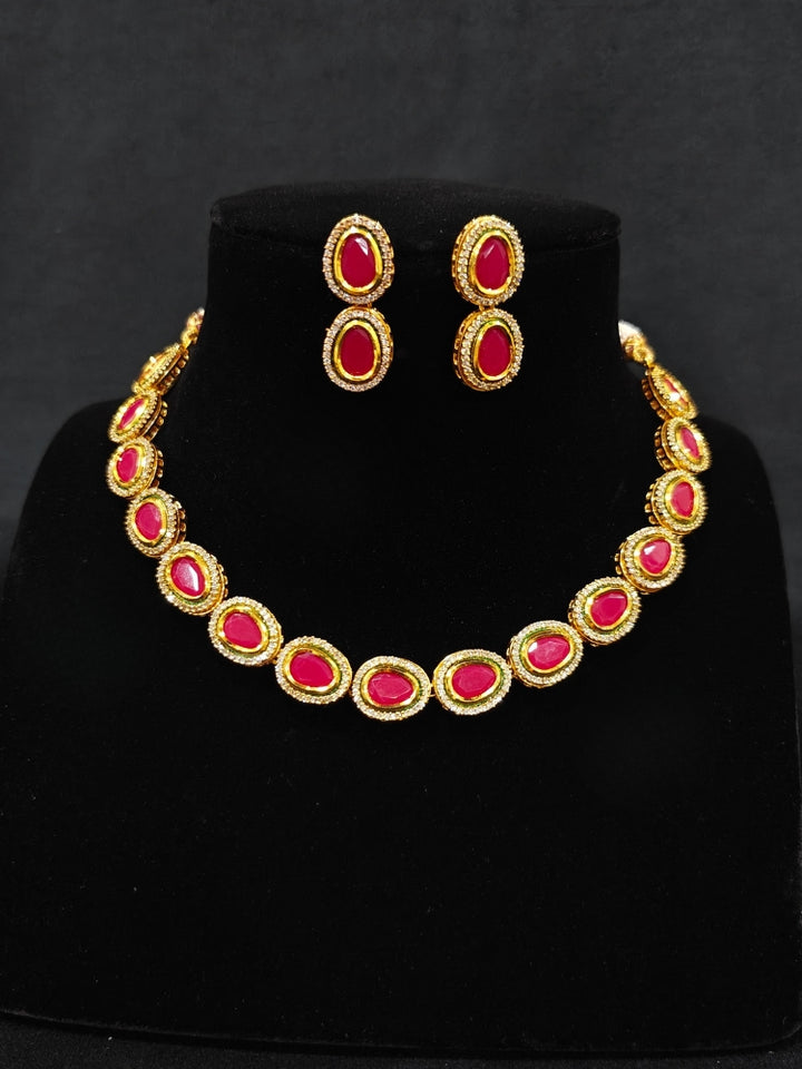 Close-up of an ornate traditional (Gold Polish) Pink Collar jewellery set and earrings with American Diamond and Pink Colored Stone. Festive Diwali outfit paired with a colorful Colored Stone necklace. Festive celebration look enhanced with traditional Colored Stone jewelry.