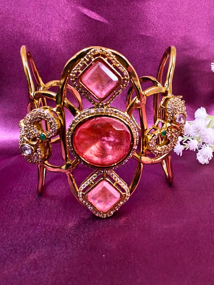 The Farah Mint Pink Bracelet (Adjustable) features intricate designs, three bold Mint Pink gemstones, and two elephant heads adorned with American diamonds —ideal for wedding ceremonies—shown on a purple fabric background.