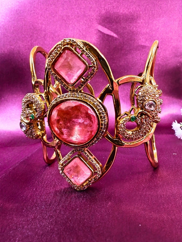 The Farah Mint Pink Bracelet (Adjustable) features intricate designs, three bold Mint Pink gemstones, and two elephant heads adorned with American diamonds —ideal for wedding ceremonies—shown on a purple fabric background.