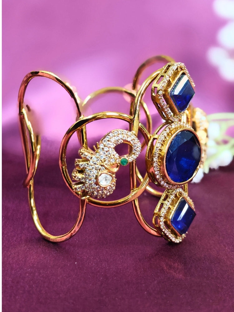 The Farah Navy Blue Bracelet (Adjustable) features intricate designs, three bold Navy Blue gemstones, and two elephant heads adorned with American diamonds —ideal for wedding ceremonies—shown on a purple fabric background.