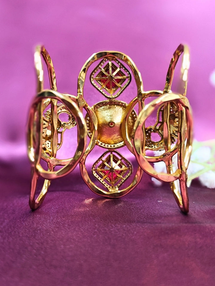 The Farah Red Bracelet (Adjustable) features intricate designs, three bold red gemstones, and two elephant heads adorned with American diamonds —ideal for wedding ceremonies—shown on a purple fabric background.