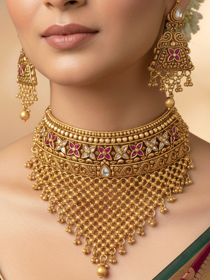 Close-up of a woman wearing an ornate traditional Heritage gold Choker jewellery set and earrings and maangtikka with Pink Colored tone. Luxury wedding styling featuring an antique-inspired artificial necklace. Traditional Indian bridal look completed with a heritage artificial jewelry set.