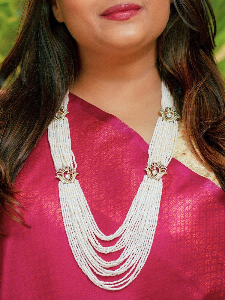 Close-up of a woman wearing an ornate traditional White Rajwadi gold Long Necklace with Pearls, American Diamond, Kundan. Festive Diwali outfit enhanced with a Rajwadi artificial necklace. Festive look completed with a luxury Rajwadi imitation necklace.