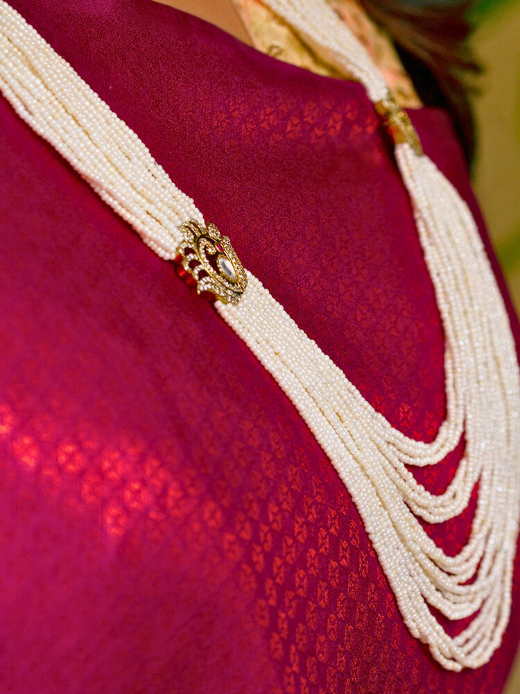 Close-up of a woman wearing an ornate traditional White Rajwadi gold Long Necklace with Pearls, American Diamond, Kundan. Festive Diwali outfit enhanced with a Rajwadi artificial necklace. Festive look completed with a luxury Rajwadi imitation necklace.