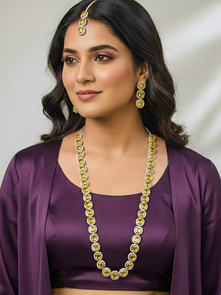 "Elegant woman wearing a luxurious artificial diamond necklace with yellow colored stone with matching earrings and matching maangtikka, perfect for high-profile wedding receptions and formal galas. This high-end artificial diamond jewelry set combines style, elegance, and affordability for special occasions."
