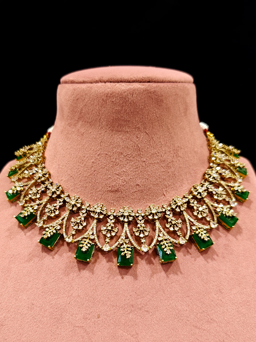A glamorous artificial diamond and emerald green colored stone designer necklace paired with chic earrings, perfect for bridal wear. This high-quality artificial diamond jewelry set is the ideal choice for modern brides looking for a budget-friendly option with timeless sparkle."