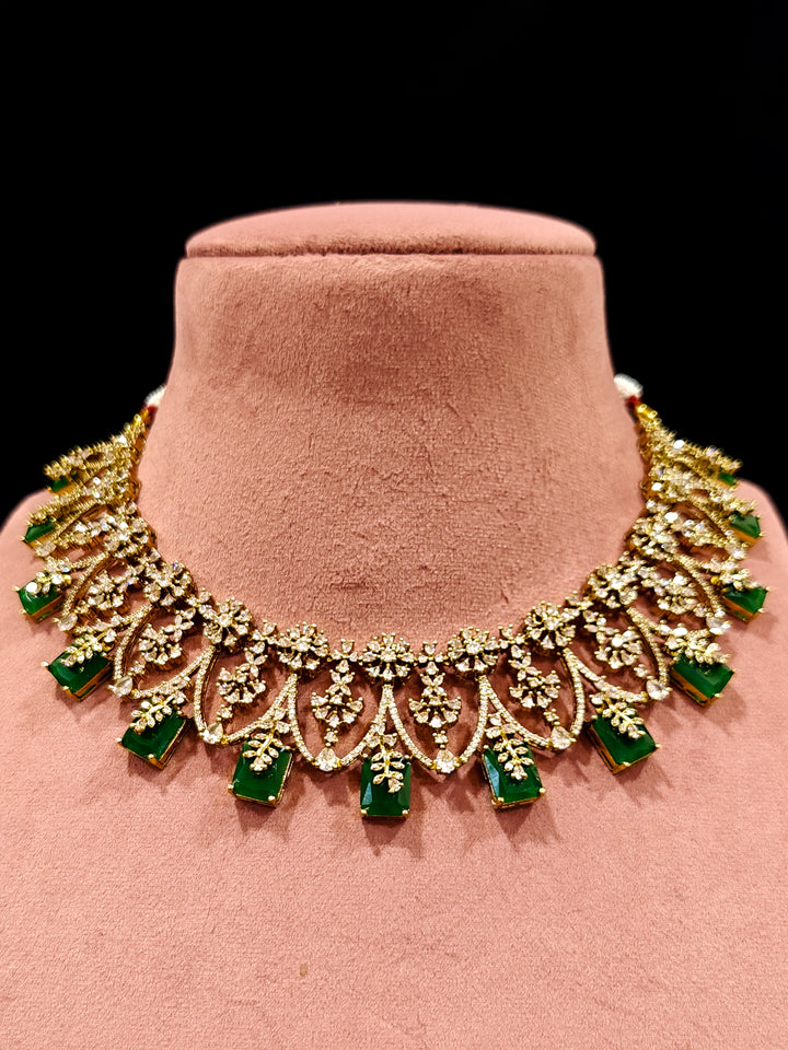 A glamorous artificial diamond and emerald green colored stone designer necklace paired with chic earrings, perfect for bridal wear. This high-quality artificial diamond jewelry set is the ideal choice for modern brides looking for a budget-friendly option with timeless sparkle."