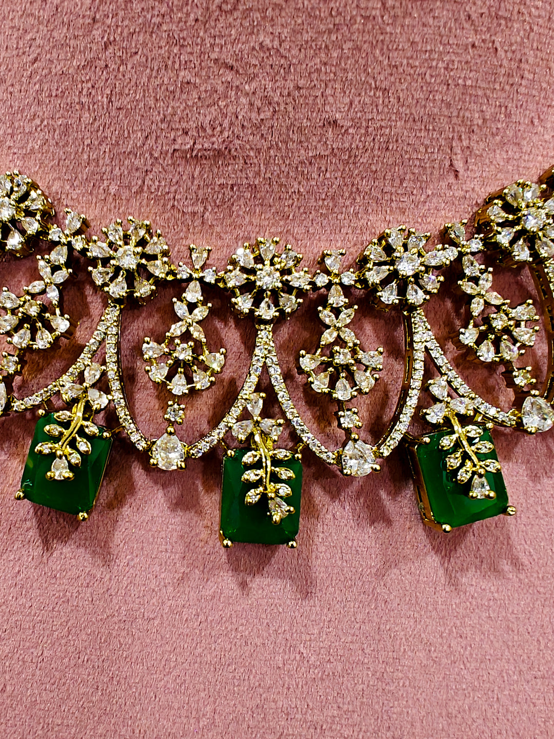 A glamorous artificial diamond and emerald green colored stone designer necklace paired with chic earrings, perfect for bridal wear. This high-quality artificial diamond jewelry set is the ideal choice for modern brides looking for a budget-friendly option with timeless sparkle."