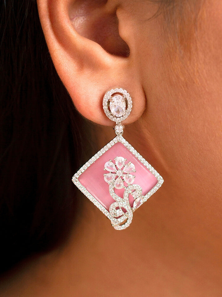 Close-up of a woman wearing an ornate Western Pink (Silver Polish) Colored Pendant set and earrings with American Diamond and Colored Stones. Festive Diwali outfit styled with an American diamond artificial necklace. Reception-ready look featuring a statement American diamond jewelry set.