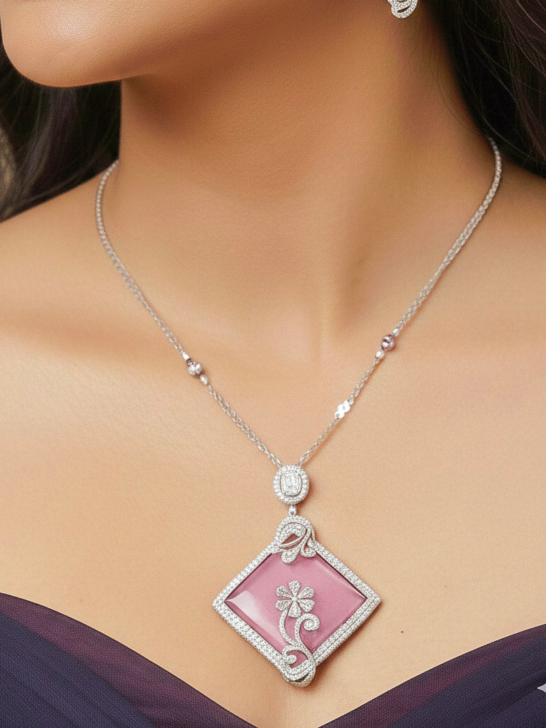 Close-up of a woman wearing an ornate Western Pink (Silver Polish) Colored Pendant set and earrings with American Diamond and Colored Stones. Festive Diwali outfit styled with an American diamond artificial necklace. Reception-ready look featuring a statement American diamond jewelry set.
