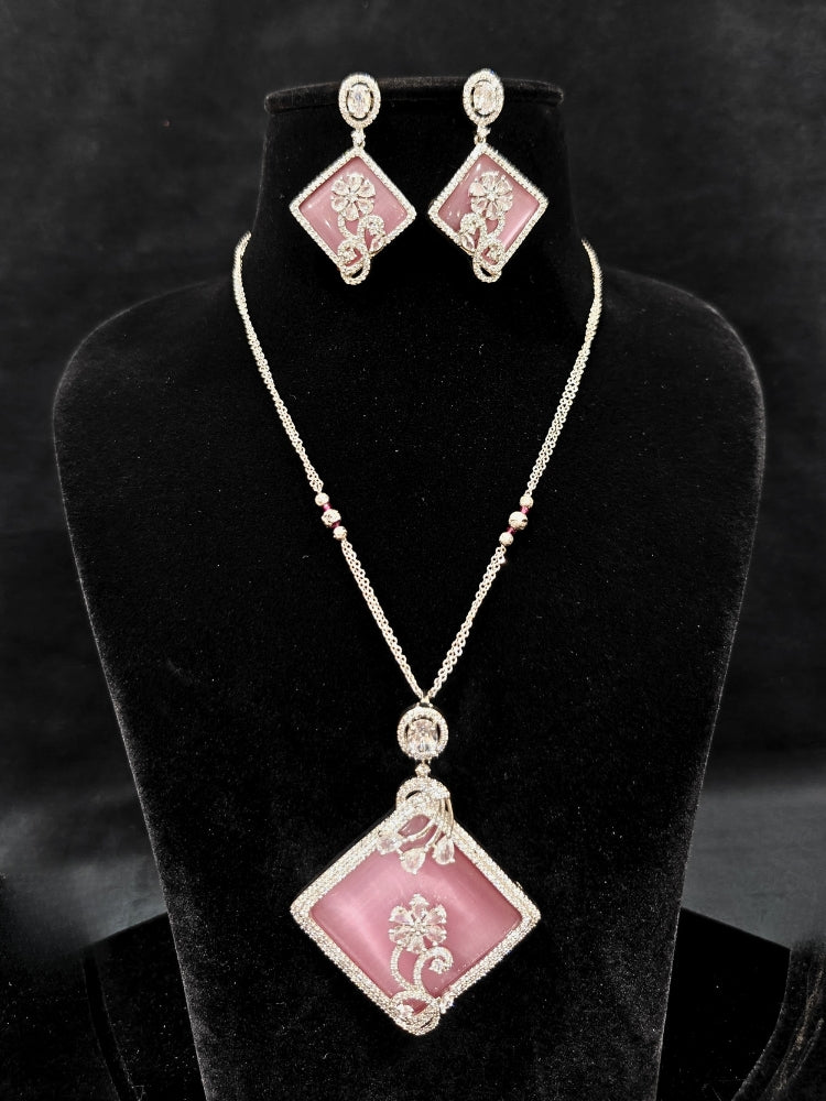 Close-up of an ornate Western Pink (Silver Polish) Colored Pendant set and earrings with American Diamond and Colored Stones. Festive Diwali outfit styled with an American diamond artificial necklace. Reception-ready look featuring a statement American diamond jewelry set.