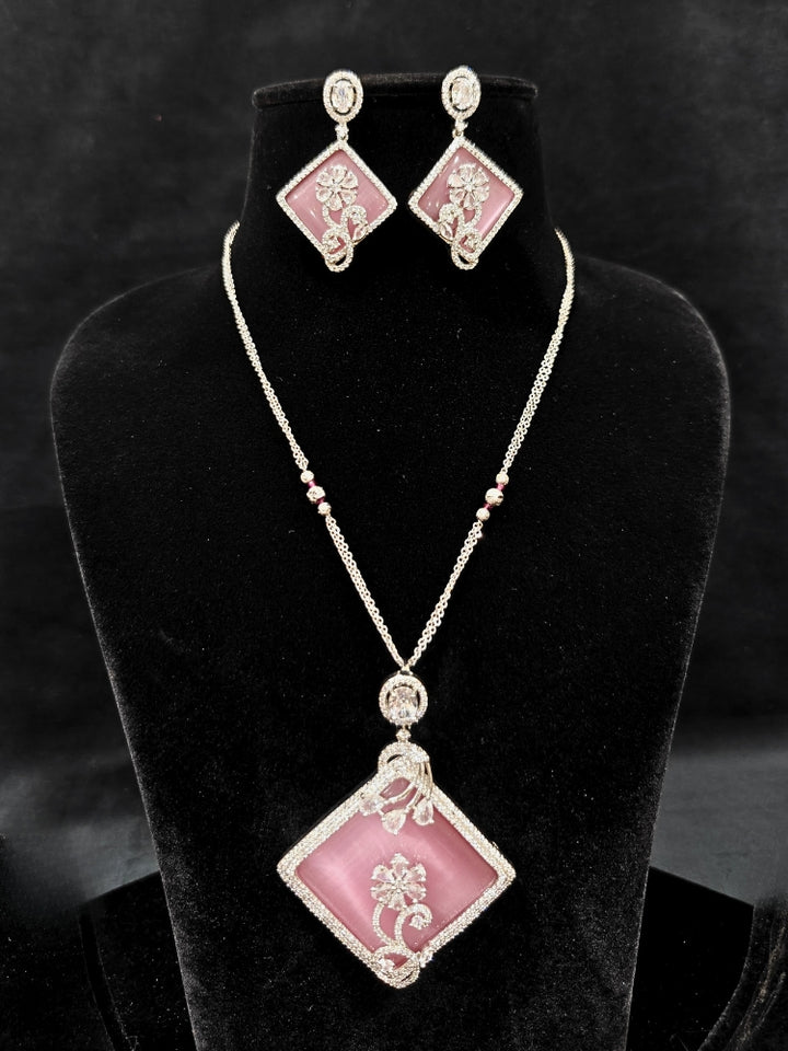 Close-up of an ornate Western Pink (Silver Polish) Colored Pendant set and earrings with American Diamond and Colored Stones. Festive Diwali outfit styled with an American diamond artificial necklace. Reception-ready look featuring a statement American diamond jewelry set.