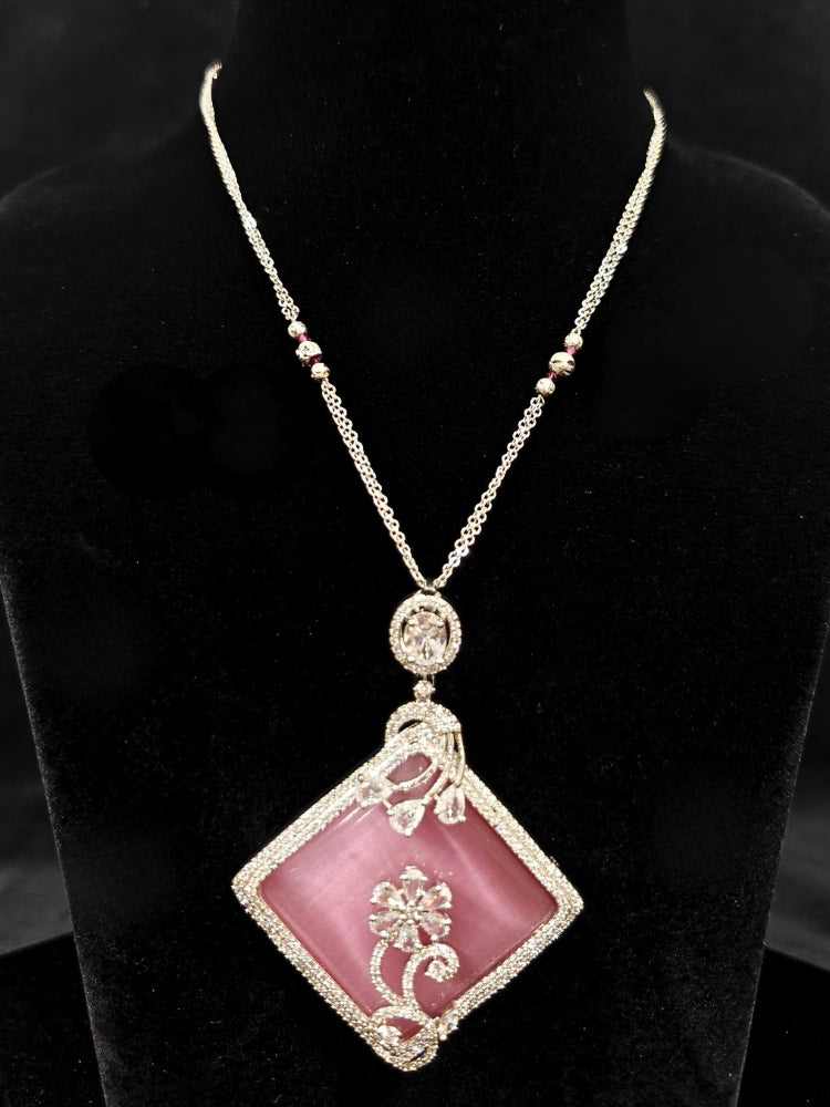 Close-up of an ornate Western Pink (Silver Polish) Colored Pendant set and earrings with American Diamond and Colored Stones. Festive Diwali outfit styled with an American diamond artificial necklace. Reception-ready look featuring a statement American diamond jewelry set.