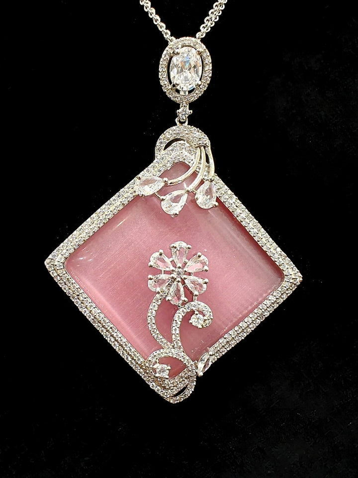 Close-up of an ornate Western Pink (Silver Polish) Colored Pendant set and earrings with American Diamond and Colored Stones. Festive Diwali outfit styled with an American diamond artificial necklace. Reception-ready look featuring a statement American diamond jewelry set.