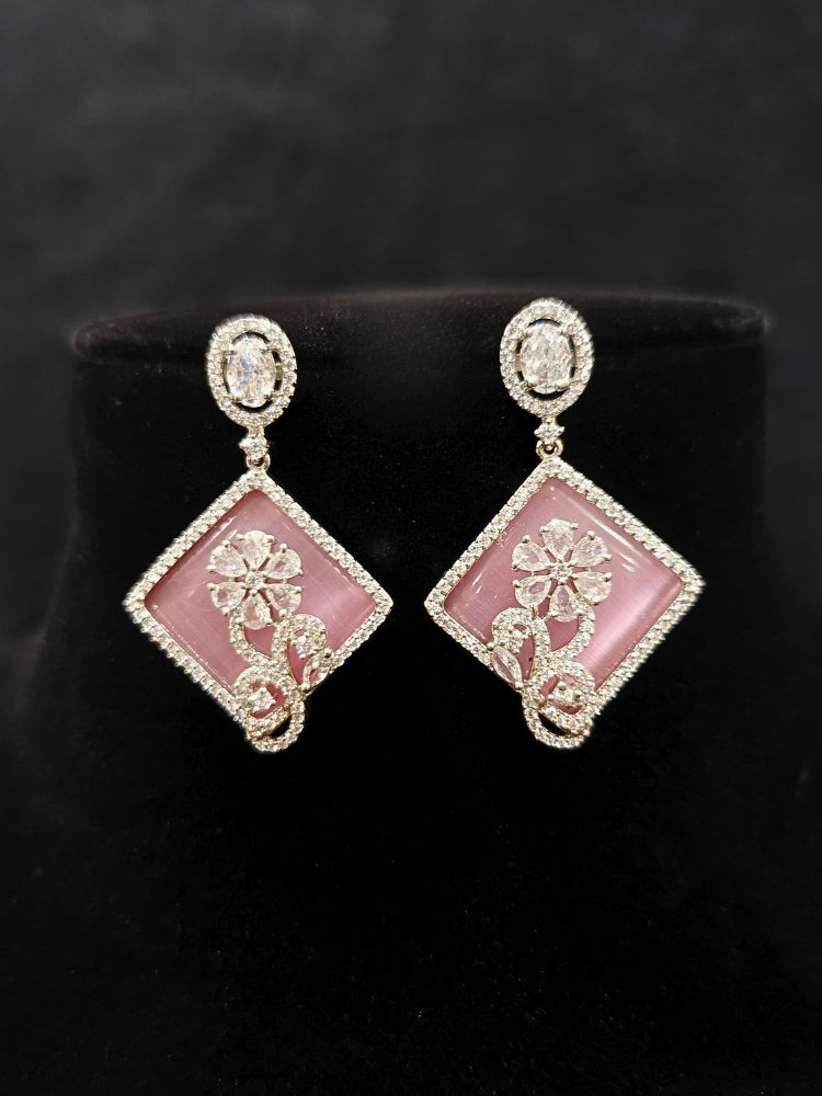 Close-up of an ornate Western Pink (Silver Polish) Colored Pendant set and earrings with American Diamond and Colored Stones. Festive Diwali outfit styled with an American diamond artificial necklace. Reception-ready look featuring a statement American diamond jewelry set.