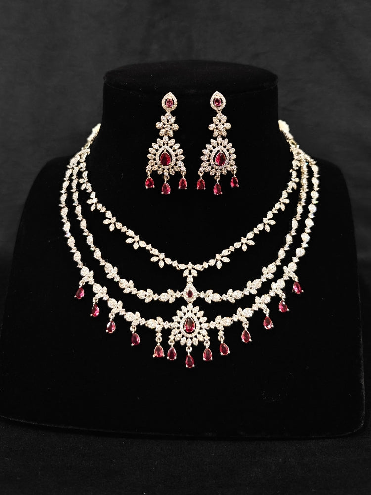 Close-up of an ornate Indo-Western Red American Diamond Silver Collar Layered jewellery set and earrings with American Diamond and Colored Stones. Bride-to-be styled in a premium American diamond artificial necklace for her reception party. Close-up of a bridal look featuring an anti-tarnish American diamond artificial necklace.