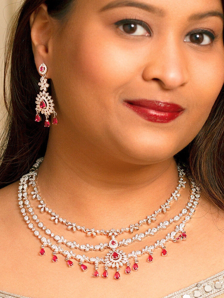 A bride-to-be wearing an exquisite artificial diamond necklace with red colored stone and matching earrings, designed for the perfect engagement look. This stunning artificial diamond jewelry set offers luxury and sophistication while being an affordable alternative to natural diamonds
