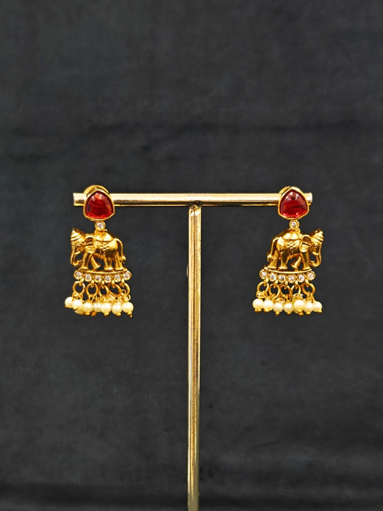 The Gajkesari Necklace Set featuring a traditional gold Collar Pink & Green necklace and matching earrings with pink and green colored stones, golden elephants and American Diamond. Close-up of a handcrafted temple imitation necklace styled with a silk saree. 