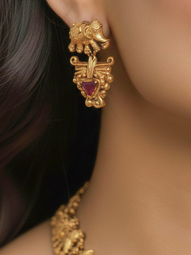 A woman wearing the Gajvani Red & White Necklace Set featuring a traditional gold collar necklace and matching earrings along with Red & White colored stones, golden elephants, paired with saree—ideal party jewelry for any festive occasion. Festive Diwali look completed with a traditional temple necklace set.