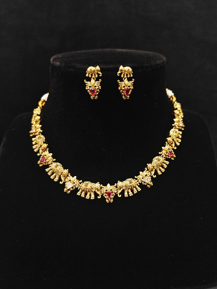 The Gajvani Red & White Necklace Set featuring a traditional gold collar necklace and matching earrings along with Red & White colored stones, golden elephants, ideal party jewelry for any festive occasion. Festive Diwali look completed with a traditional temple necklace set.
