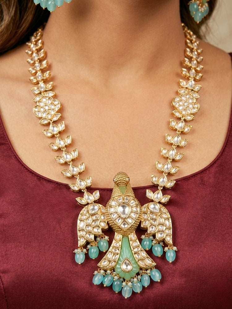 Close-up of a woman wearing an ornate traditional (Gold Polish) Sea Green Long jewellery set and earrings with Polki and Tumble Beads. Festive celebration look completed with premium imitation Polki jewelry. Woman wearing trending Polki artificial jewelry for the wedding season in India.