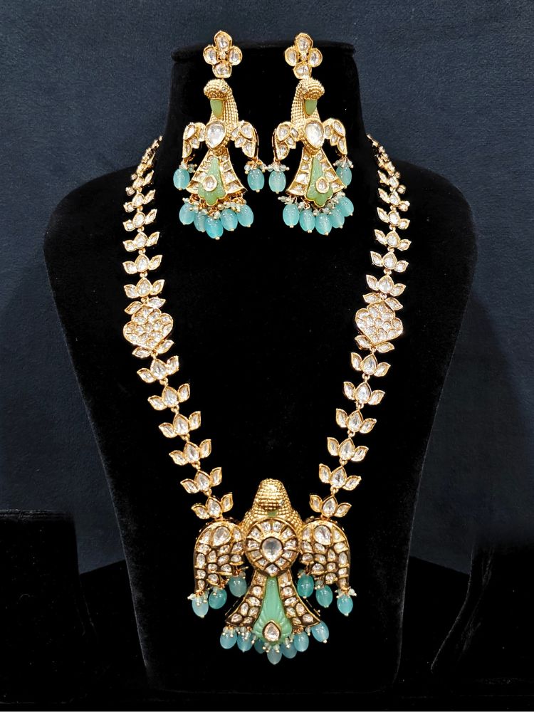 Close-up of an ornate traditional (Gold Polish) Sea Green Long jewellery set and earrings with Polki and Tumble Beads. Festive celebration look completed with premium imitation Polki jewelry. Woman wearing trending Polki artificial jewelry for the wedding season in India.