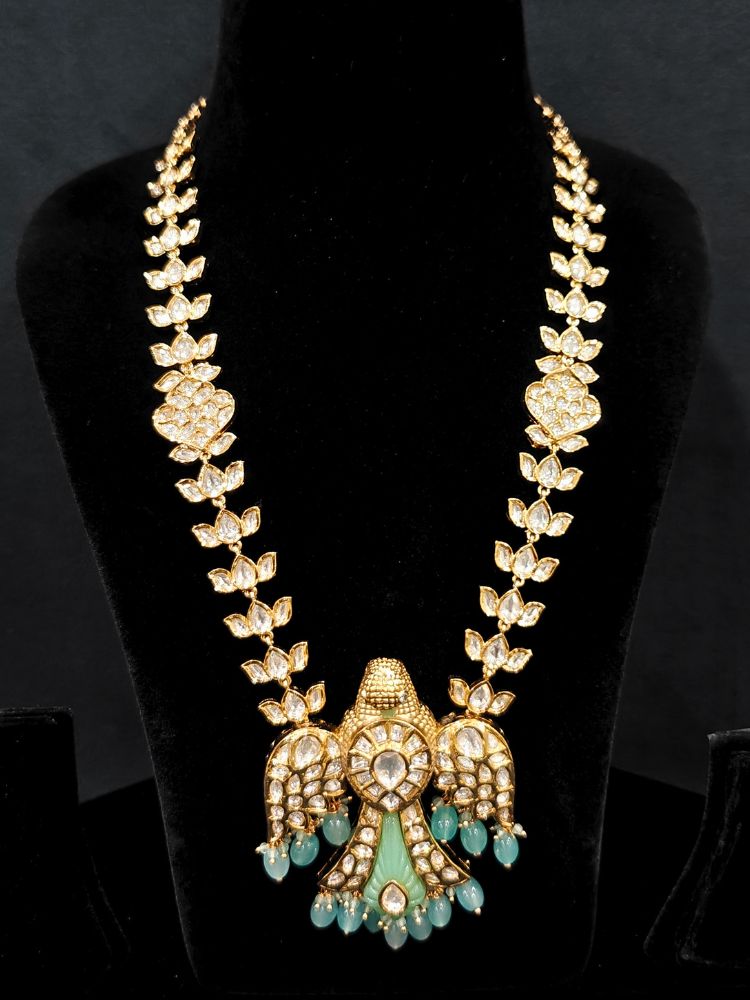 Close-up of an ornate traditional (Gold Polish) Sea Green Long jewellery set and earrings with Polki and Tumble Beads. Festive celebration look completed with premium imitation Polki jewelry. Woman wearing trending Polki artificial jewelry for the wedding season in India.