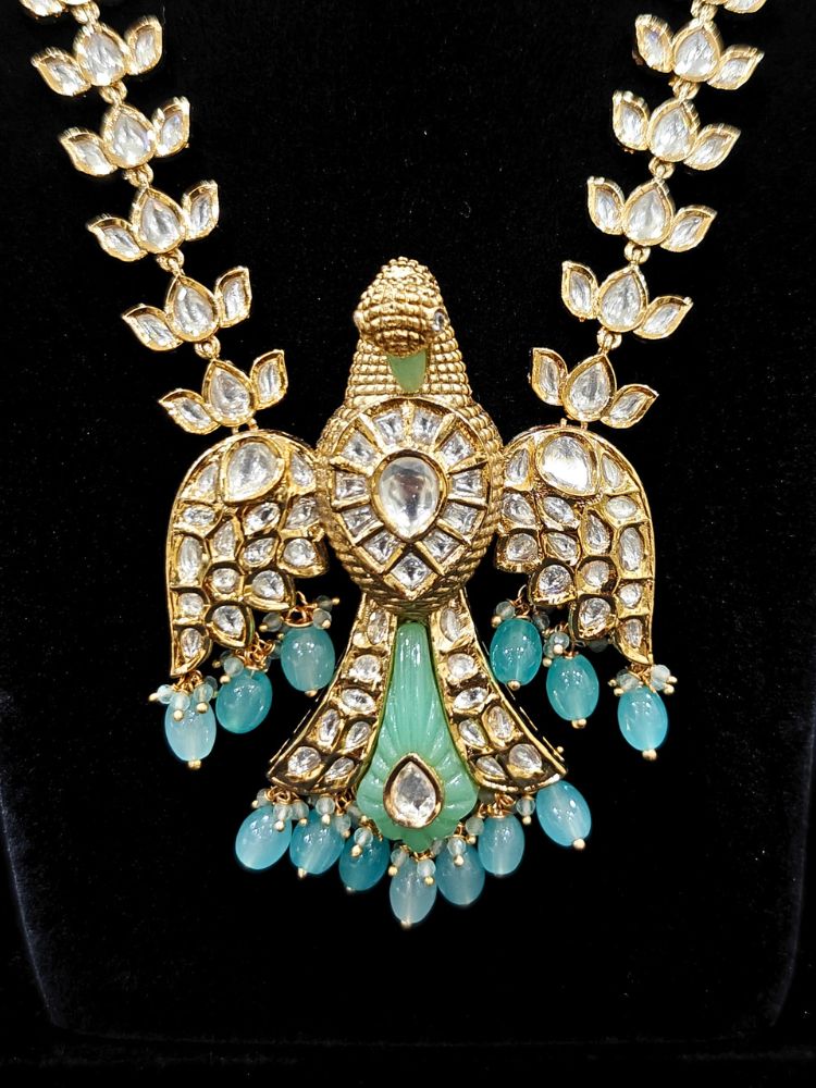 Close-up of an ornate traditional (Gold Polish) Sea Green Long jewellery set and earrings with Polki and Tumble Beads. Festive celebration look completed with premium imitation Polki jewelry. Woman wearing trending Polki artificial jewelry for the wedding season in India.