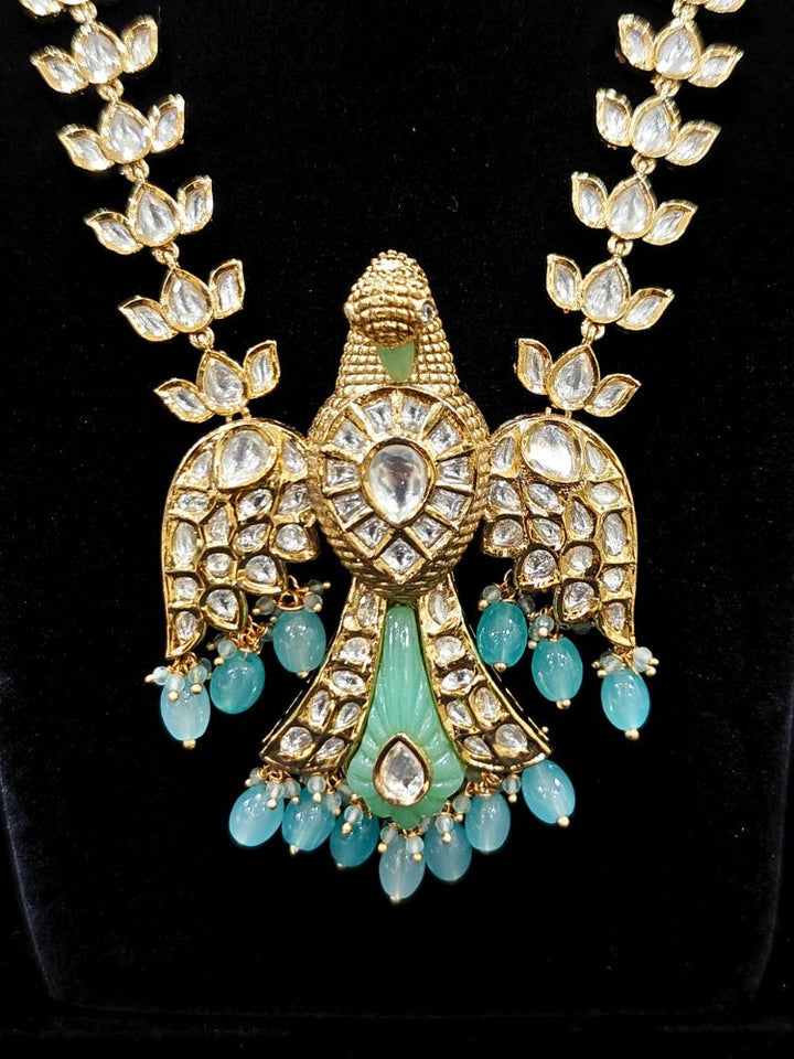 Close-up of an ornate traditional (Gold Polish) Sea Green Long jewellery set and earrings with Polki and Tumble Beads. Festive celebration look completed with premium imitation Polki jewelry. Woman wearing trending Polki artificial jewelry for the wedding season in India.