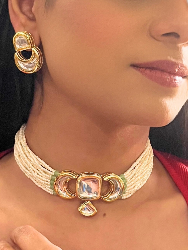 A woman wearing the Gautami Choker Necklace, Kundan Necklace Set featuring a multi-strand pearl choker with a gold and Kundan centerpiece, matching Kundan earrings, and a red top. Only her lower face is visible.